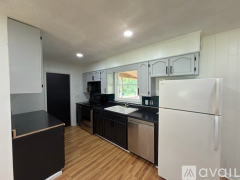 A kitchen with a black countertop and white appliances.