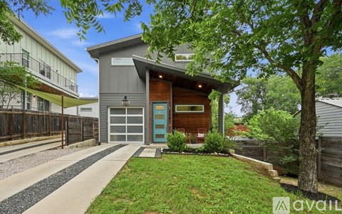 A modern house with a blue door and a garage is for sale.