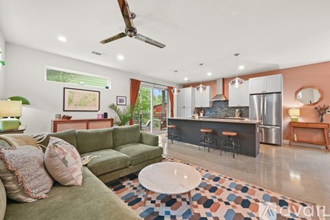 A living room with a green couch and a kitchen area in the background.