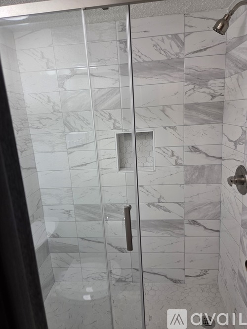A bathroom with a marble tile shower and a glass door.