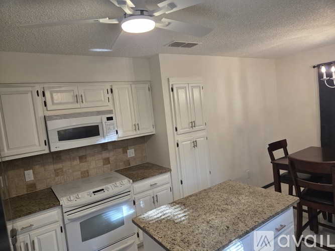 A kitchen with white cabinets and a granite countertop.