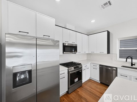 A modern kitchen with white cabinets and stainless steel appliances.