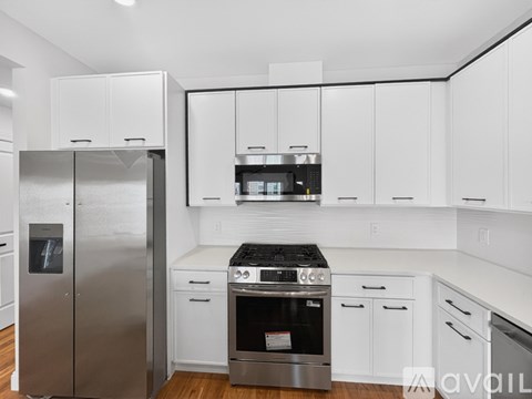 A modern kitchen with white cabinets and stainless steel appliances.