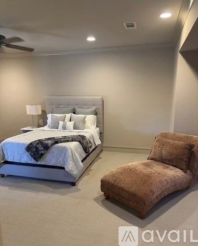 A bedroom with a large bed and a chair.