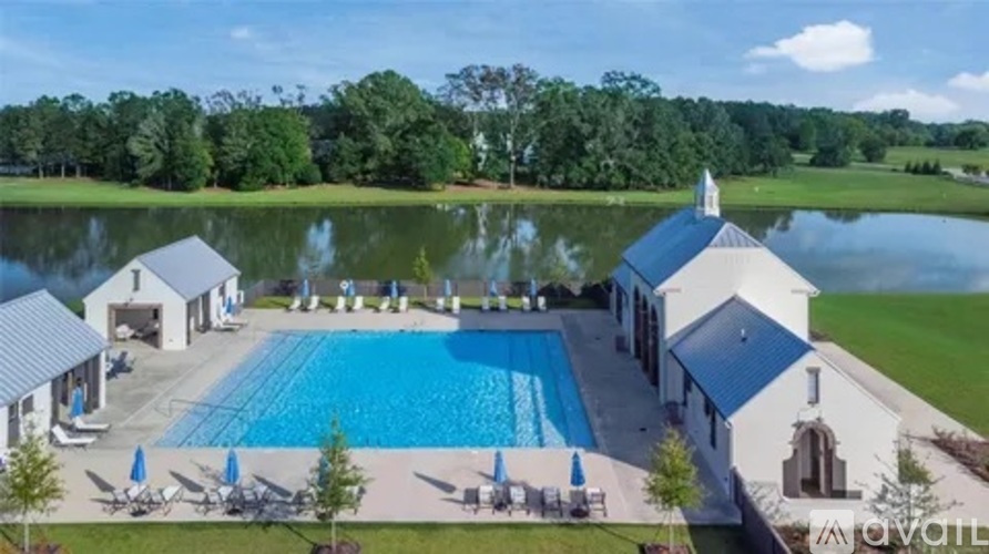 A large swimming pool surrounded by a grassy area and a building with a blue roof.