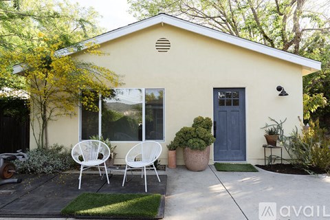 A small house with a blue door and white chairs outside.