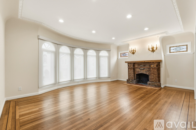 A spacious room with wooden floors and a fireplace.