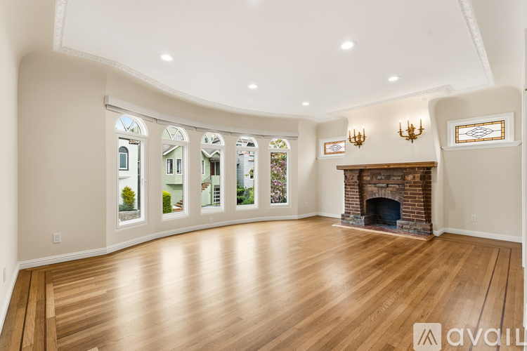 A spacious living room with wood flooring and a fireplace.