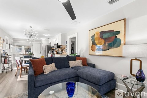 A living room with a grey couch and a painting on the wall.