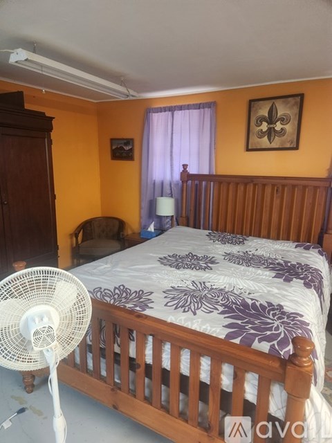 A bedroom with a bed, a fan, and a dog.