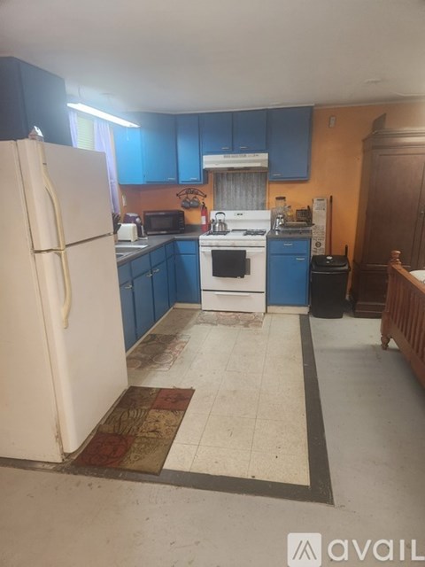 A kitchen with a white refrigerator and blue cabinets.
