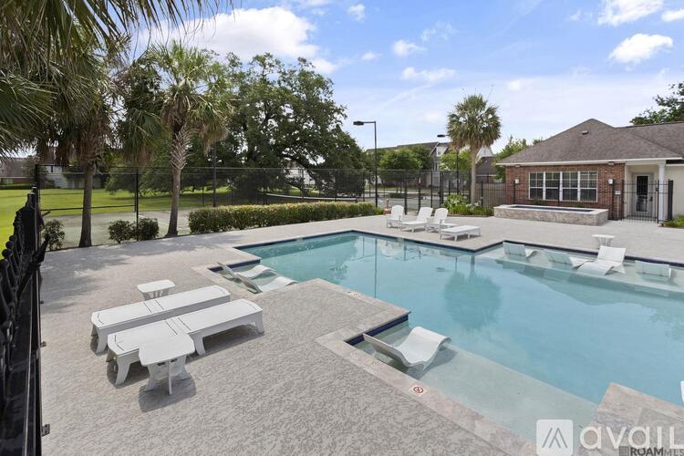 A pool area with sun loungers and a building in the background.