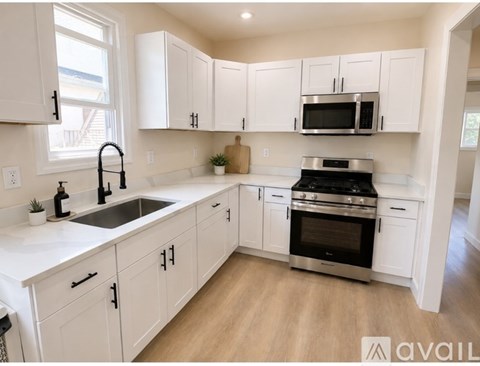 A kitchen with white cabinets and a black stove top oven.