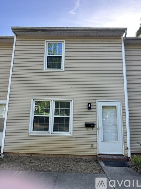 A beige house with a white door and two windows.