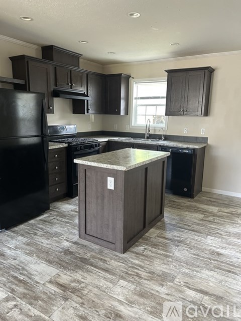 A kitchen with a black refrigerator and a wooden island.