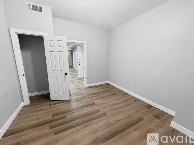 A spacious room with wooden flooring and white walls.