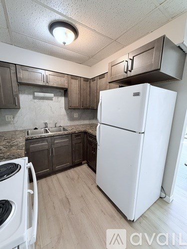A white refrigerator stands in a kitchen with wooden cabinets.