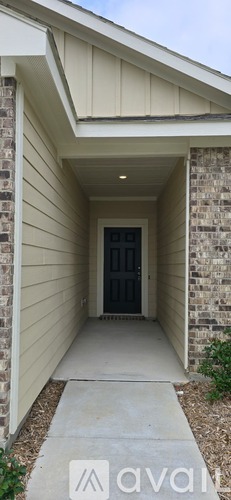 A white house with a black door and a concrete walkway.