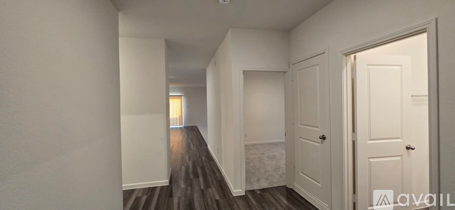 A long hallway with white walls and wood flooring.