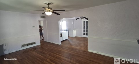 A room with a ceiling fan and a person standing in the doorway.