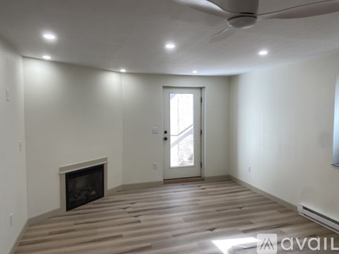 A spacious room with a fireplace and a ceiling fan.
