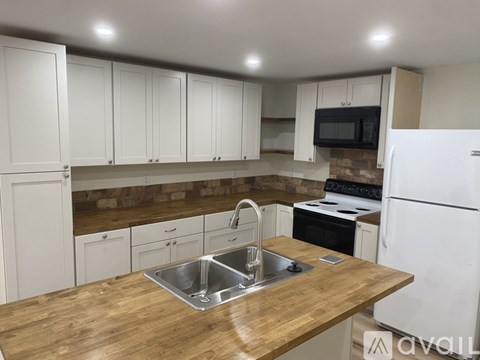 A kitchen with white cabinets and a wooden countertop.