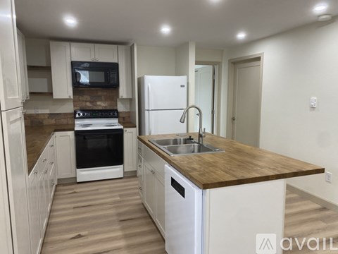 A kitchen with a white fridge, black microwave, and a wooden countertop.