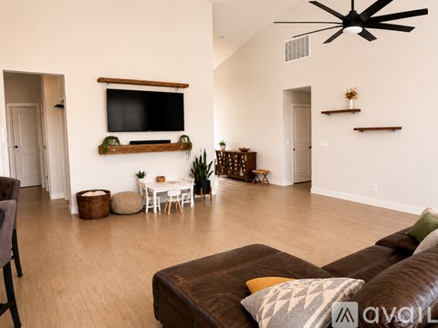 A living room with a brown couch and a flat screen TV mounted on the wall.