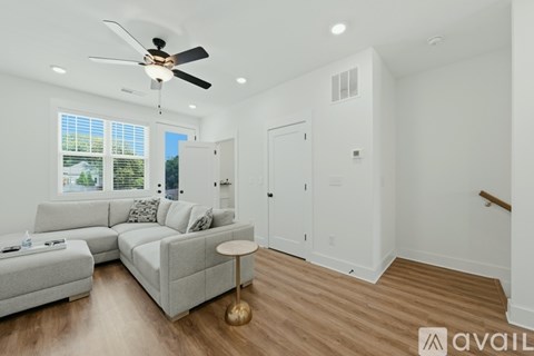 A living room with a grey sofa and a ceiling fan.