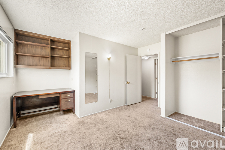 A room with a desk, shelves, and a carpeted floor.
