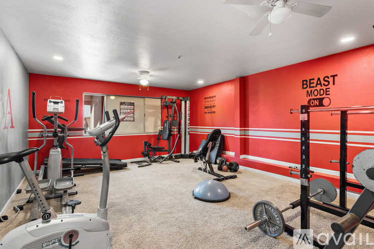 A well equipped gym with a red wall and a sign that says "Beast Mode On".