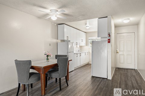 A kitchen with a table and chairs in the foreground and a refrigerator in the background.