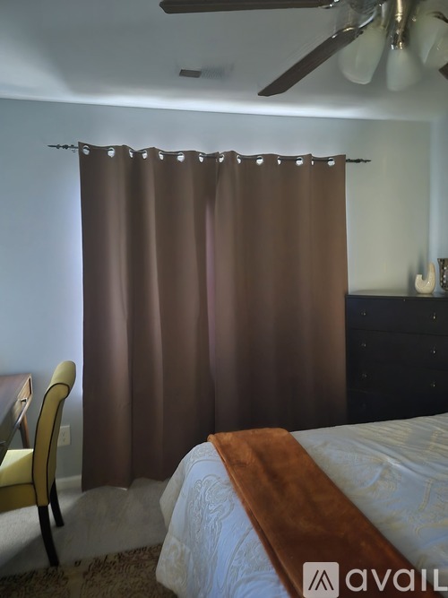A bedroom with a brown curtain and a white bed.