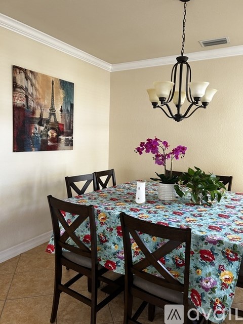 A dining room with a floral tablecloth and a chandelier.