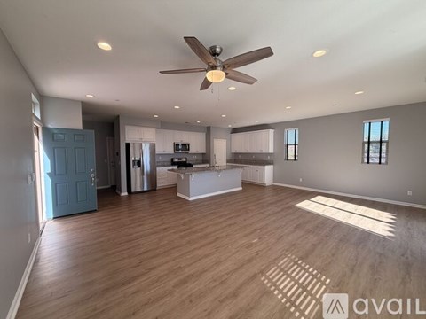 A spacious room with a kitchen area and a ceiling fan.