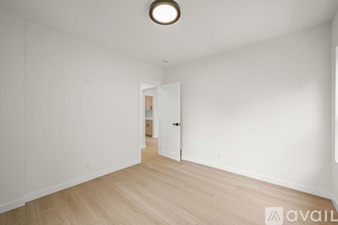 A room with a wooden floor and white walls, with a door on the right side.