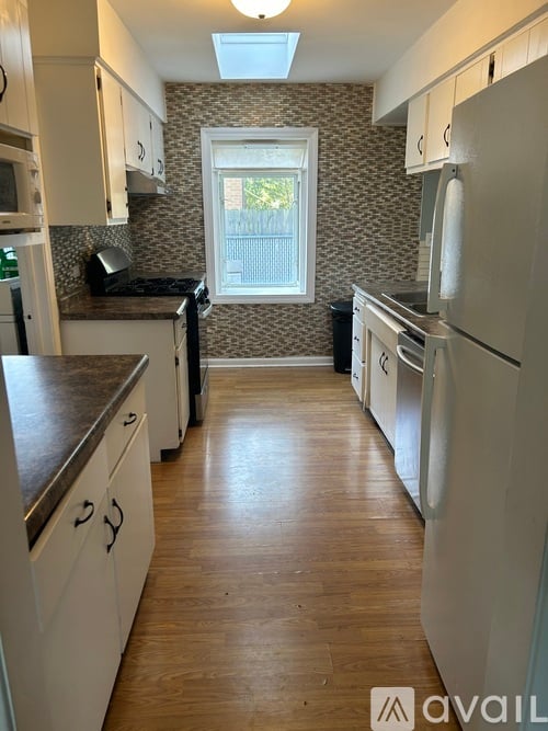 A kitchen with white cabinets and a window.