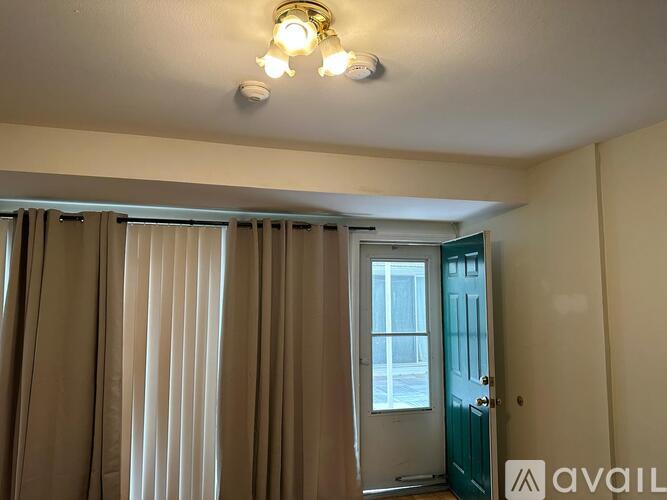 A room with a window covered by curtains and a door on the right side.