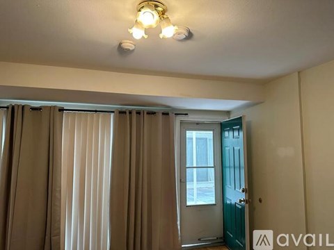 A room with a window covered by curtains and a door on the right side.