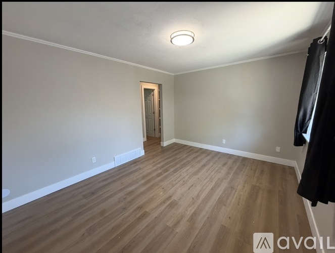 A room with wooden flooring and a door in the background.
