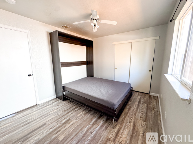 A bedroom with a bed, a ceiling fan, and a window.