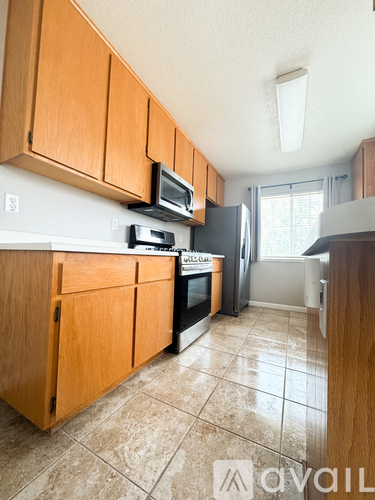 A kitchen with wooden cabinets and a tiled floor.