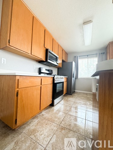 A kitchen with wooden cabinets and a tiled floor.
