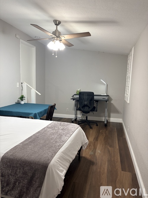 A bedroom with a bed, desk, and chair.