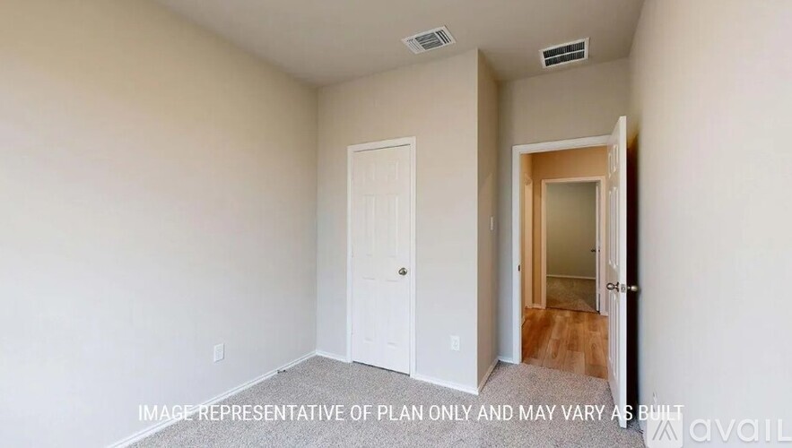 A room with a white door and a wooden floor leading to another room.