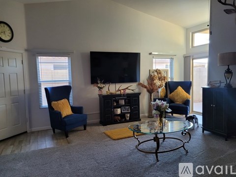 A living room with a blue chair and a glass coffee table.