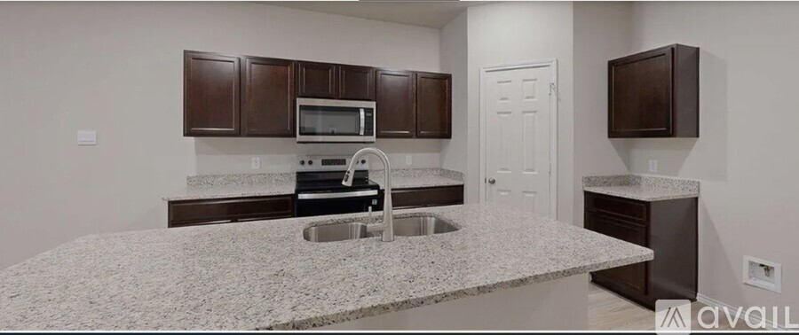A kitchen with granite countertops and dark brown cabinets.