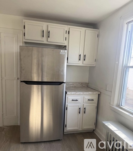 A kitchen with a stainless steel refrigerator and white cabinets.