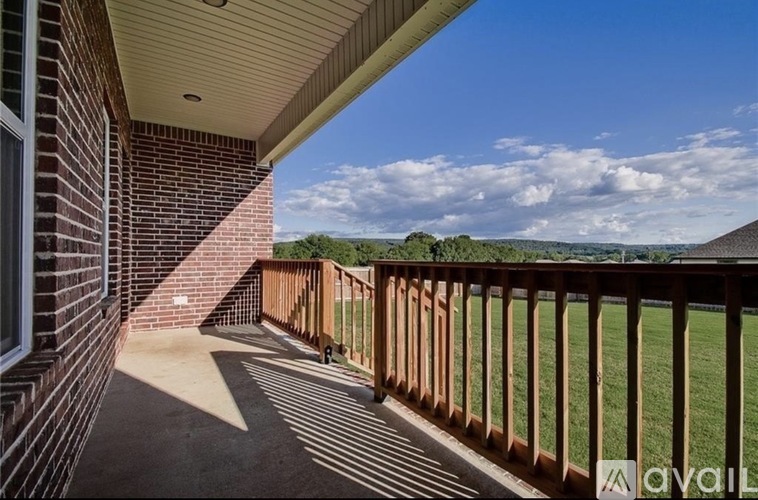 A balcony with a wooden railing and a brick building.