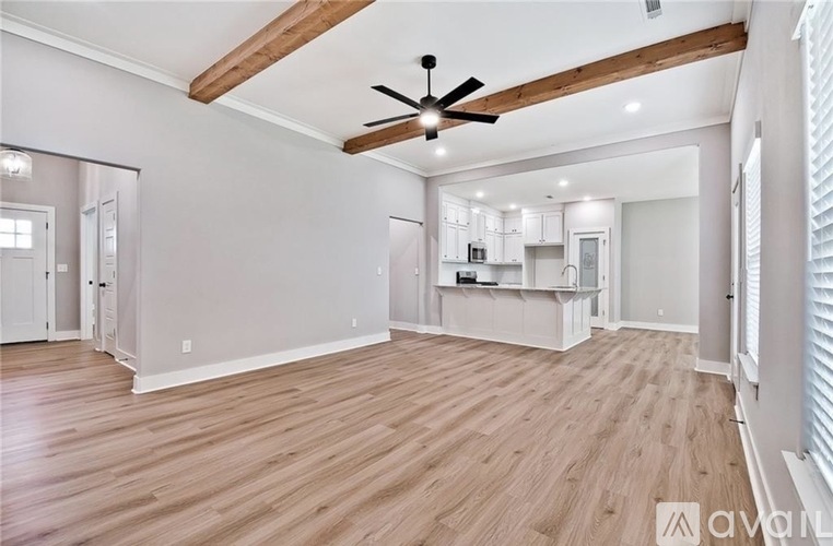 A spacious room with wooden floors and a ceiling fan.